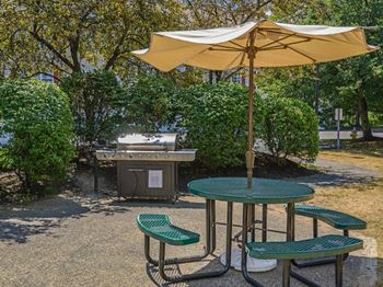 a table and chairs with an umbrella and a grill  at Residences at Westborough Station, Westborough